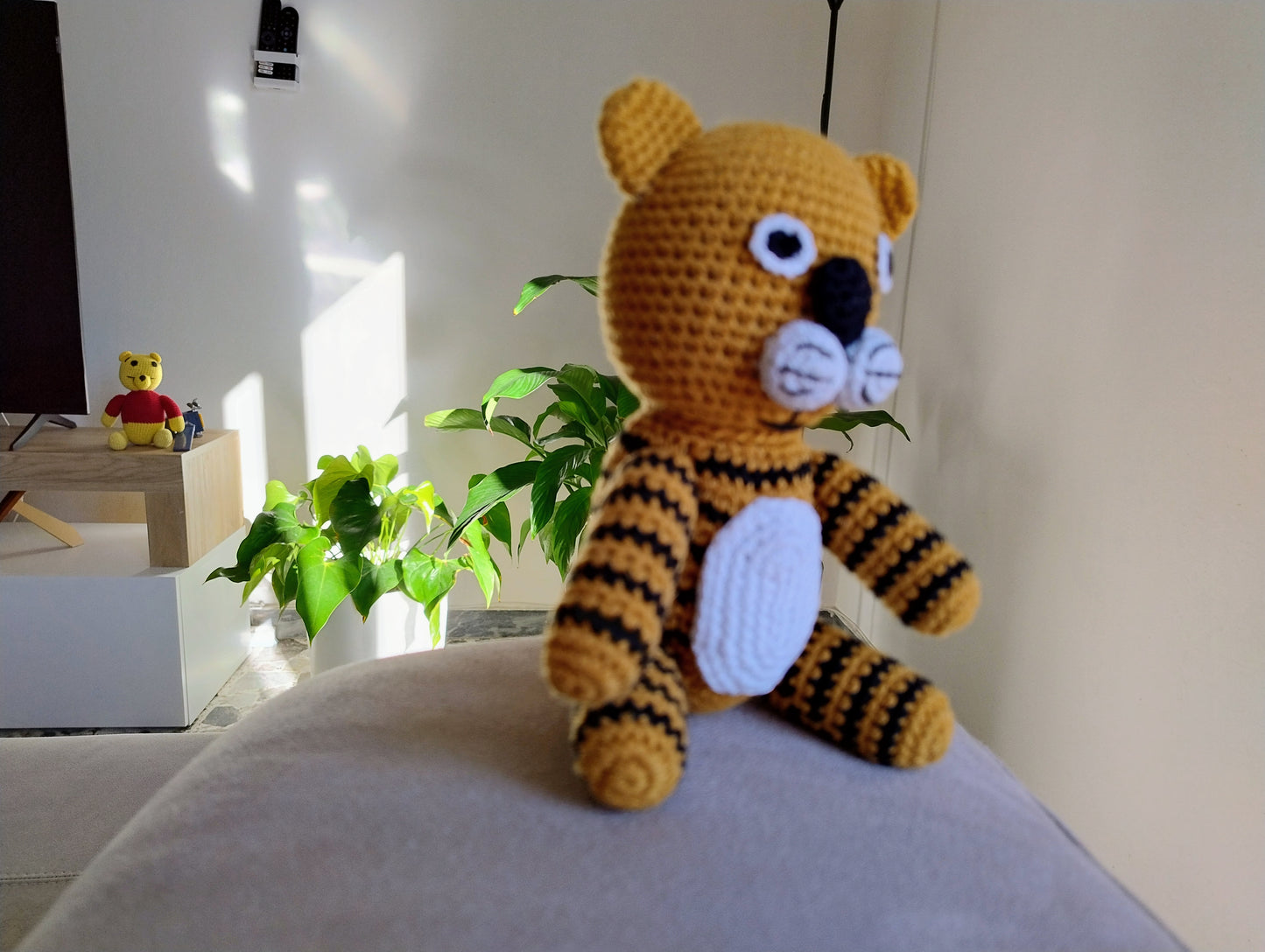 Handcrafted crochet tiger toy displayed on modern sofa with houseplants, artisan nursery decor gift for contemporary homes
