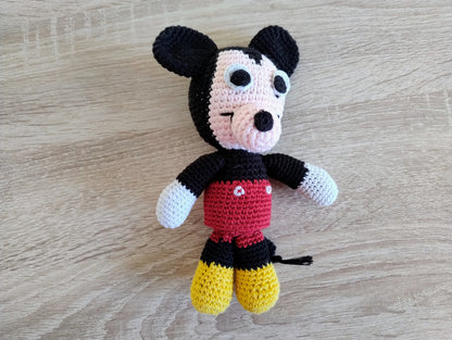 Handmade mouse amigurumi lying on a light wood surface; highlighting the intricate crochet stitches and high-quality yarn of this Italian-made stuffed toy