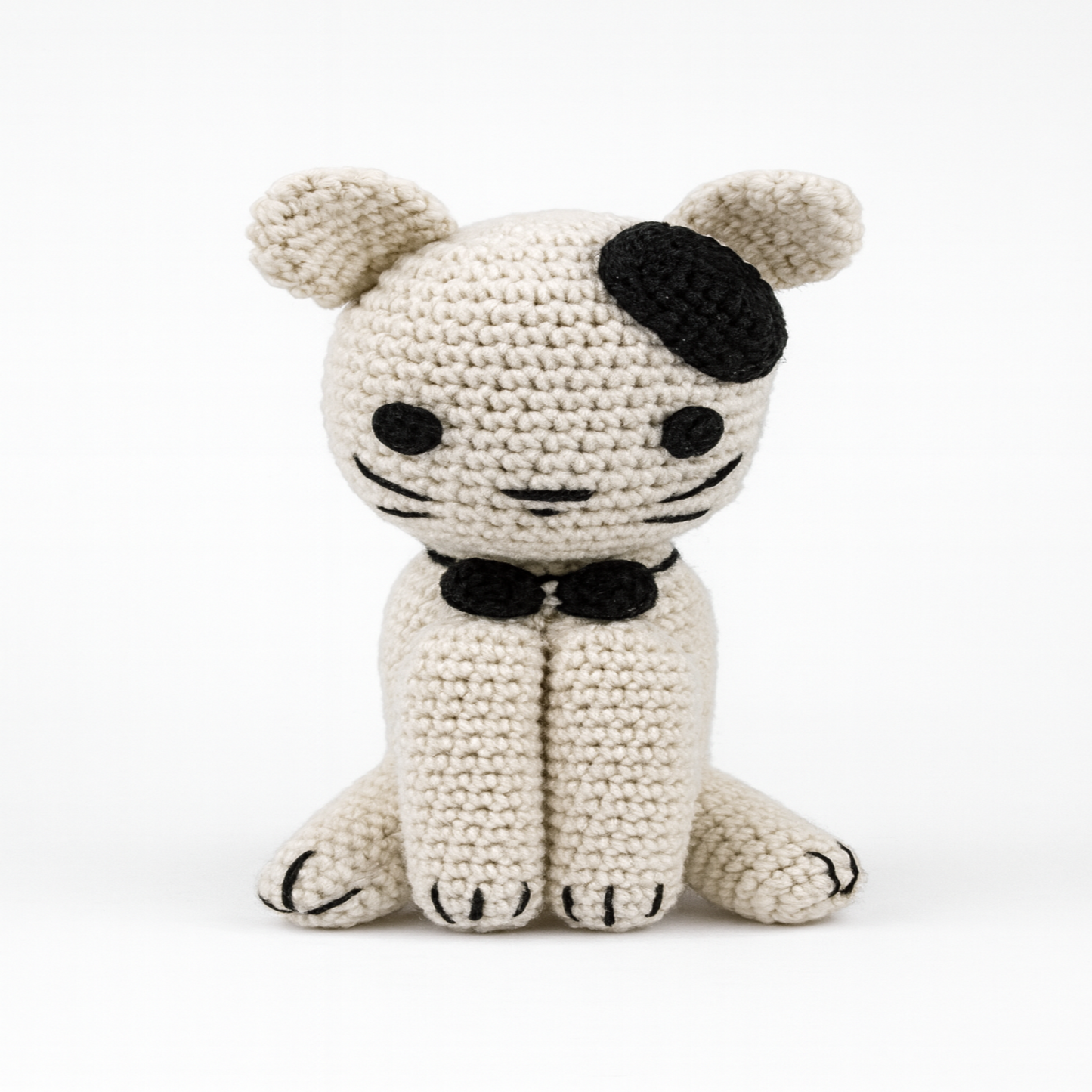 Close-up front view of a crocheted kitten, showcasing the neat 'V' stitches of the amigurumi technique, pointed ears, and a perfectly centered face.