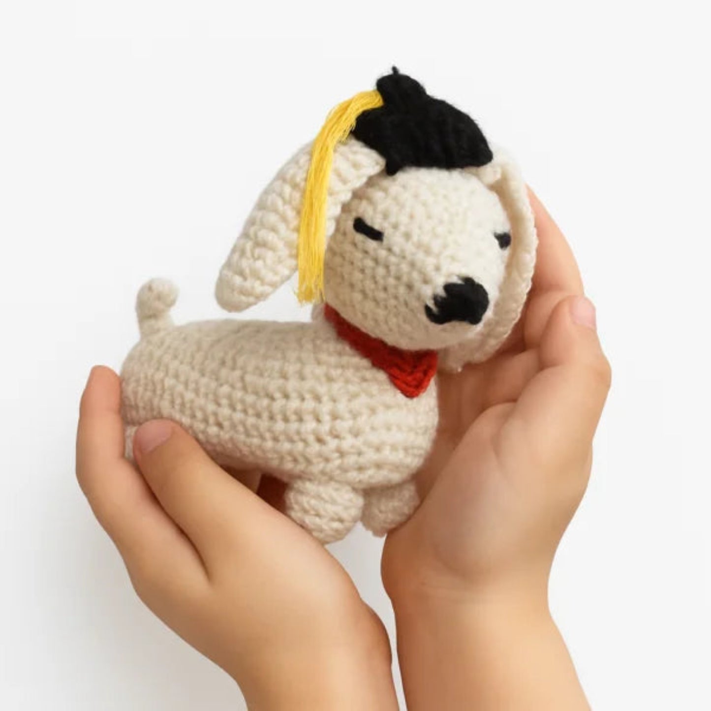 Handmade crochet graduation puppy amigurumi held in hand showing size
