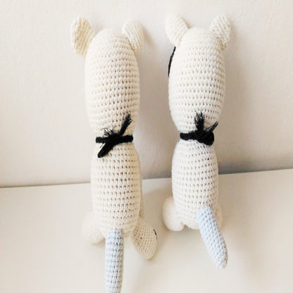 Back view of a pair of handmade amigurumi crochet cats with long tails sitting together
