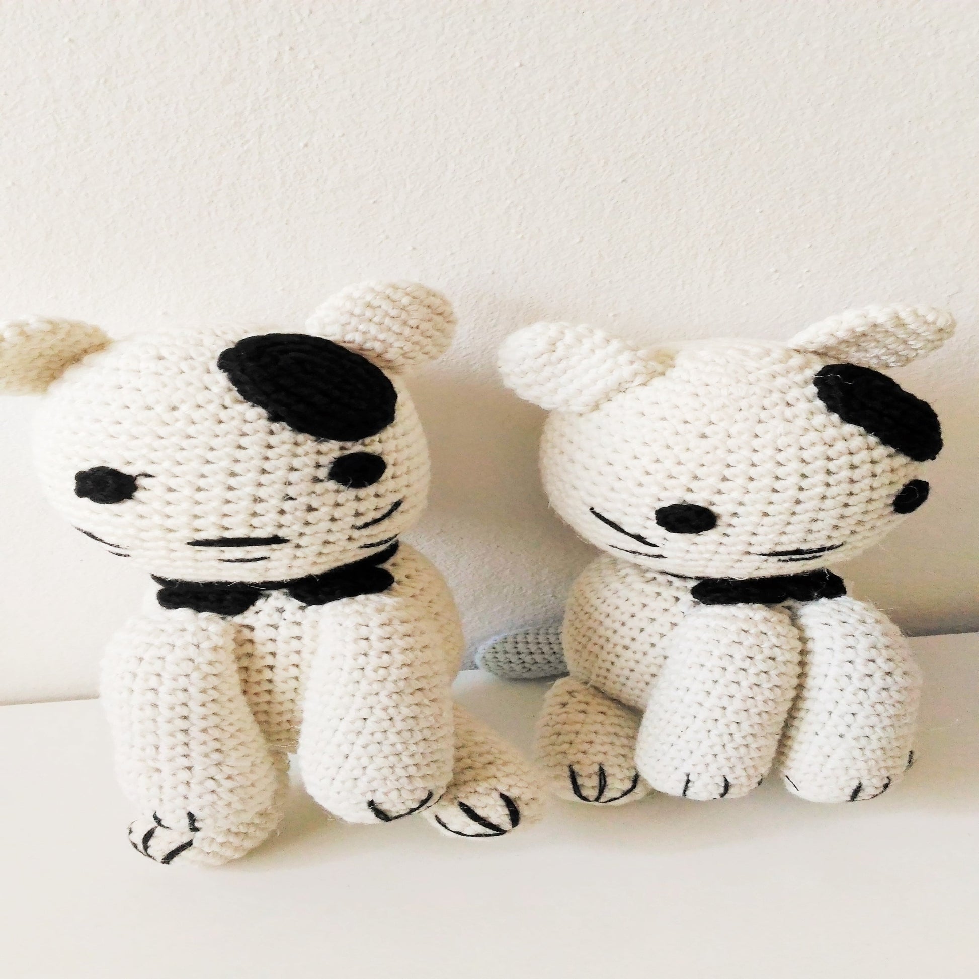 Two handmade amigurumi crochet cats amigurumi on a white surface front view
