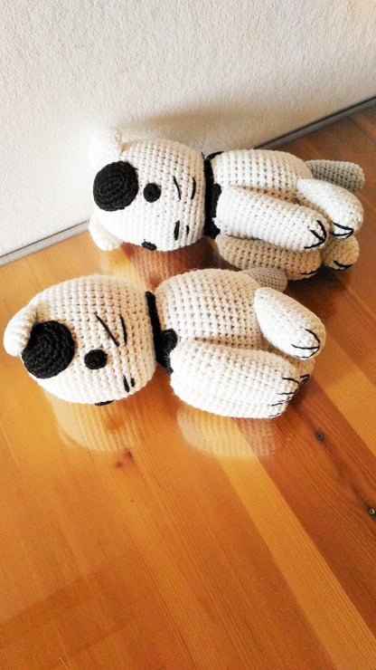 Two handmade amigurumi cats sleeping on a rustic wooden glass table surface