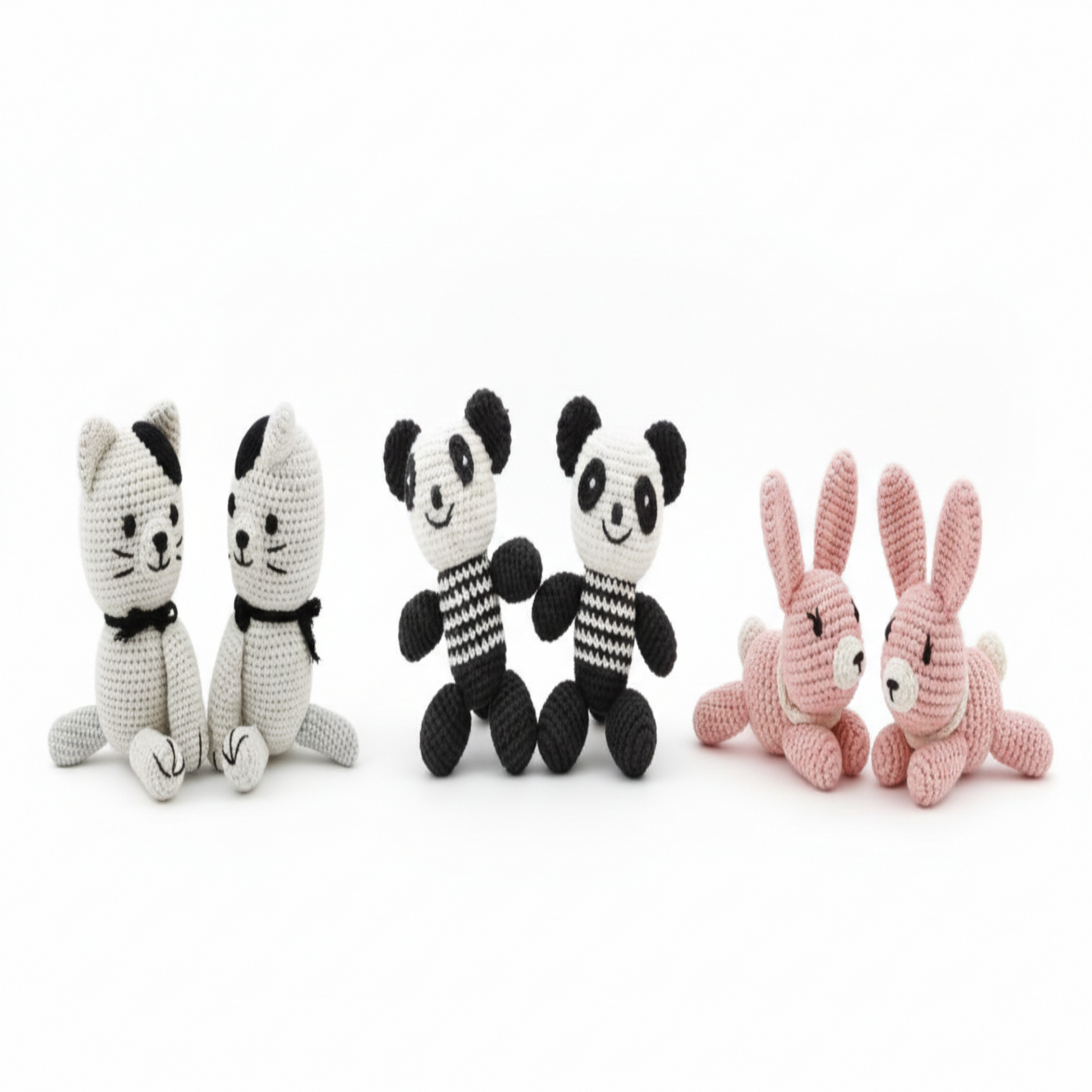 Two pink crochet bunnies in a lying pose on a white background.