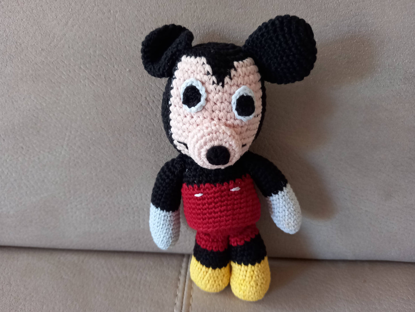 Close-up of a standing handmade mouse amigurumi on a neutral background, highlighting the intricate crochet stitches and high-quality yarn craftsmanship