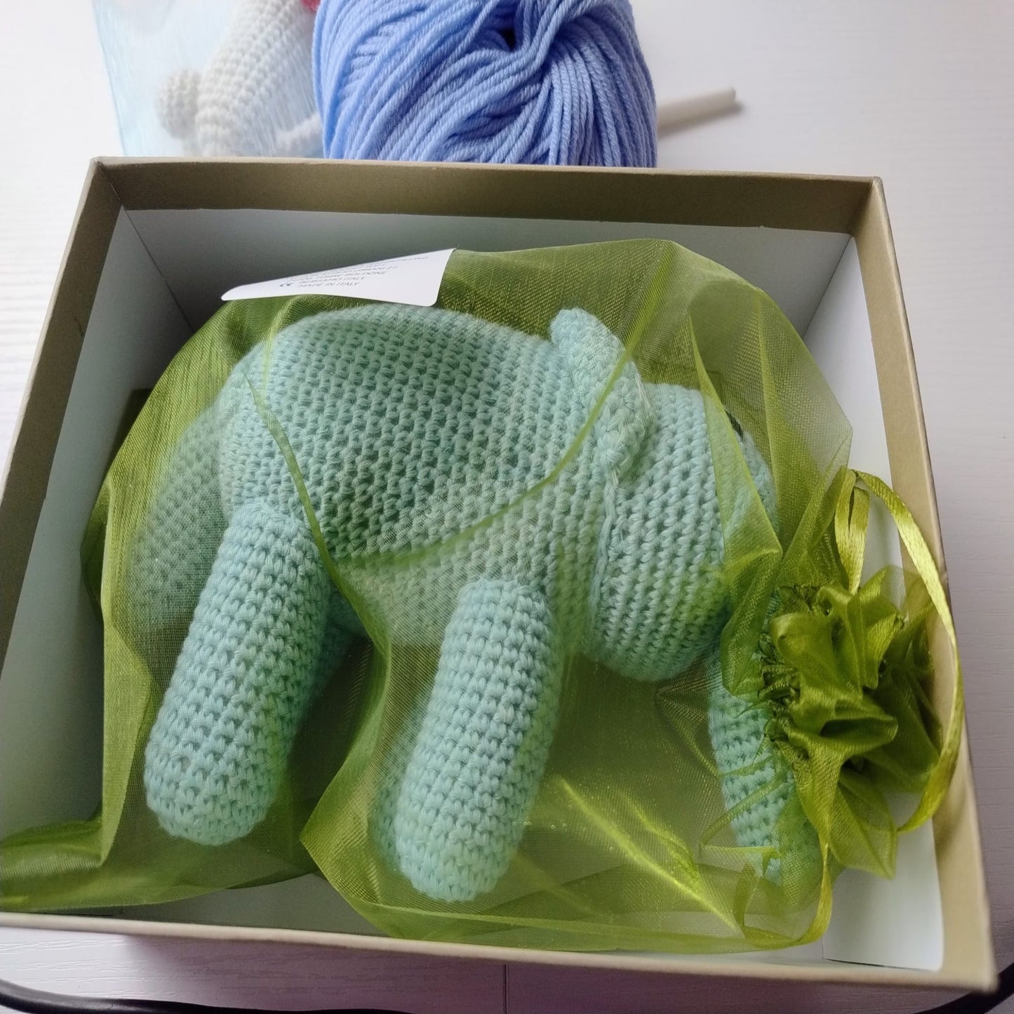 Green crochet elephant in a gift box with green mesh wrap.